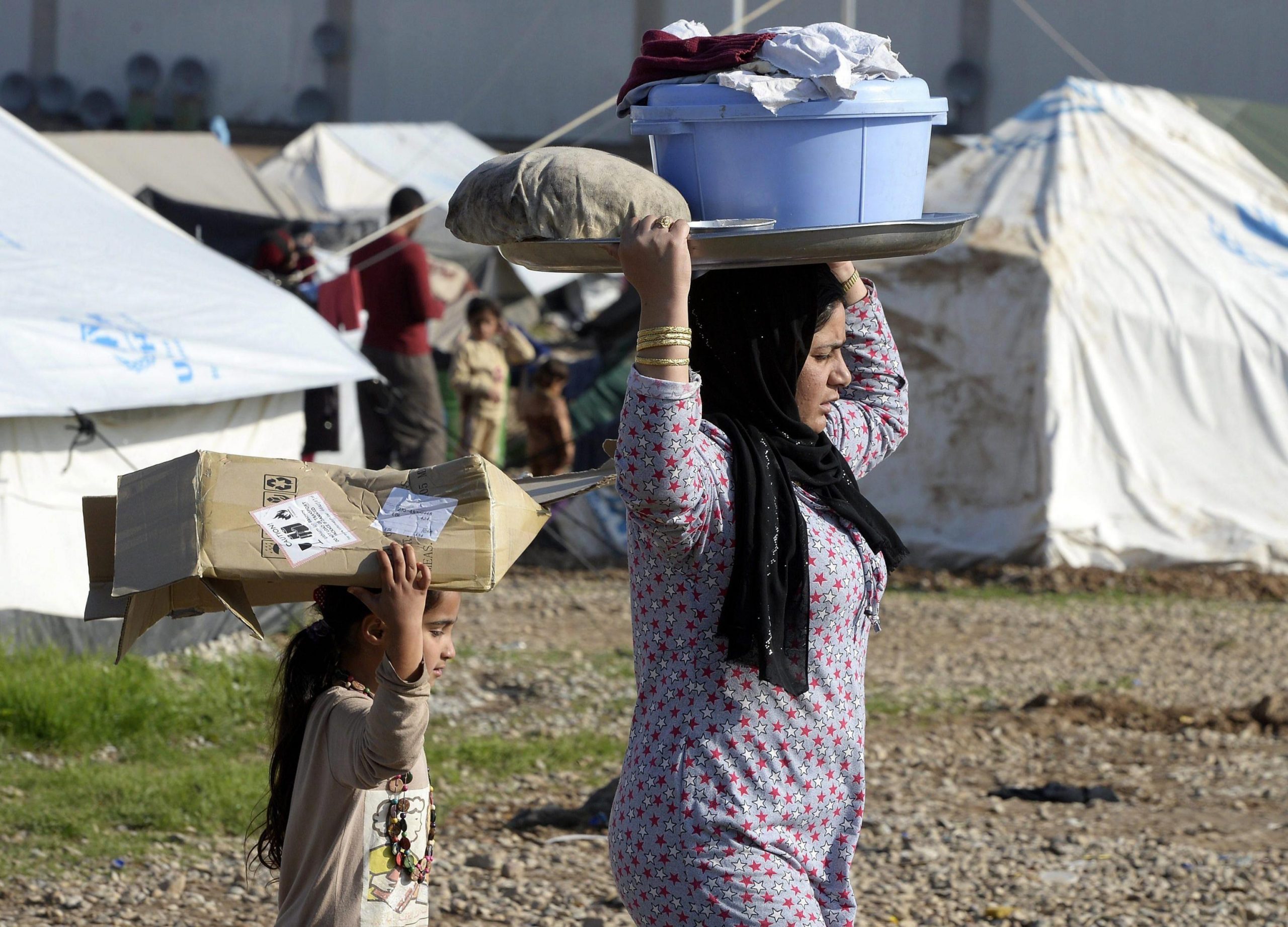 epa04524894 A Yazidi woman and child transport laundry on their heads at the Baharka refugee camp, near the capital of the Iraqi-Kurdish region Erbil, Iraq, 11 December 2014. According to reports the camp houses over 3,600 people, some of the estimated 1.5 million people of various ethnic and religious groups forced to flee their homes as fighters from the group calling themselves the Islamic State (IS) took control, many finding shelter in the predominantly Kurdish north of Iraq.  EPA/DAREK DELMANOWICZ POLAND OUT